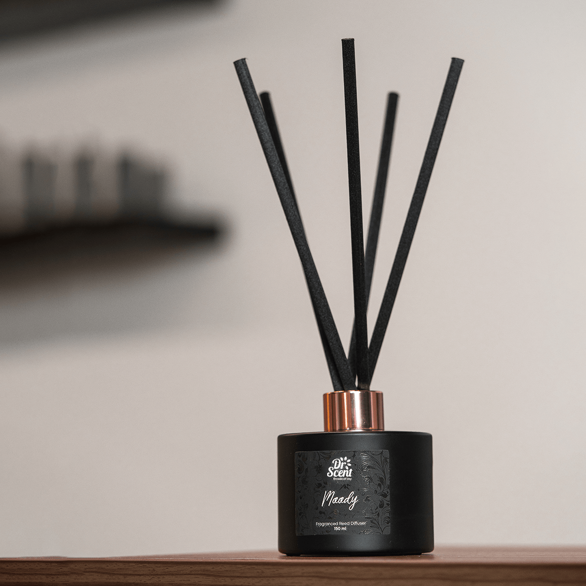 Moody reed diffuser with black reeds on a wooden shelf